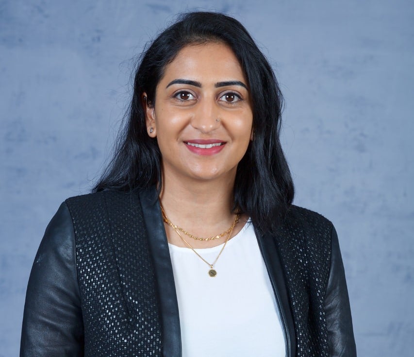 Dr Poonam Pannu headshot in front of blue background 