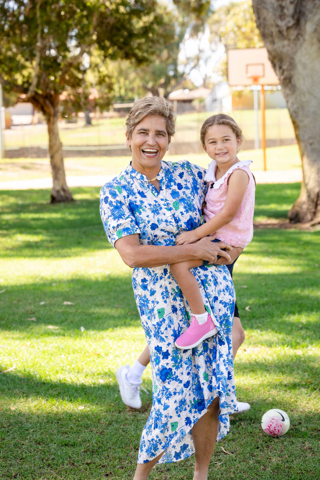 Prof Desi Silva with a small girl on her hip both smiling in a park